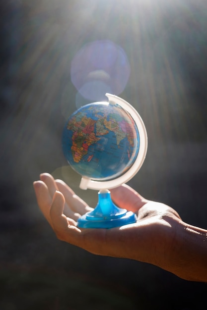 Mano che tiene il piccolo globo del mondo Foto Gratuite