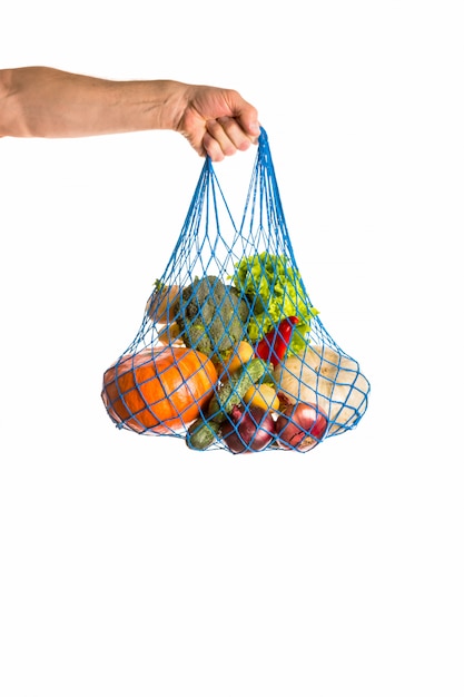 Mano dell'uomo irriconoscibile che tiene un sacco di verdure miste. cibo sano e concetto di rifiuti zero. isolato su bianco Foto Premium