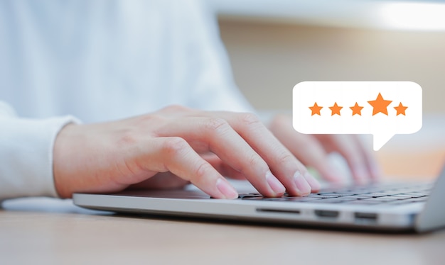Mano uomo cliente digitando sul portatile tastiera per dare un buon punteggio per rivedere il servizio con feedback di valutazione a stelle Foto Premium