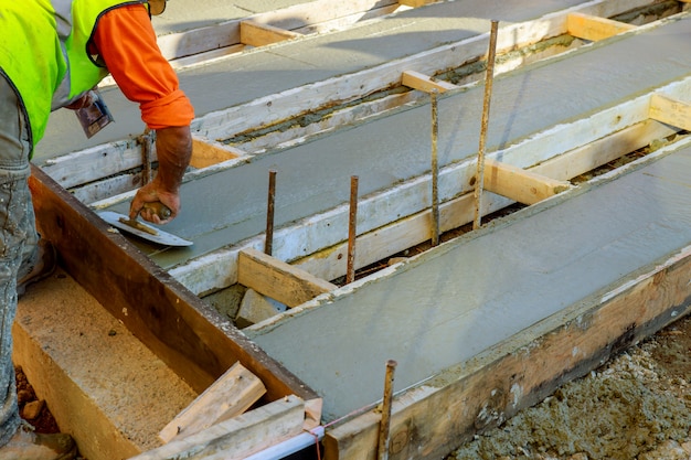 Mason che costruisce un cemento del massetto ai lavori del pavimento. versando la pavimentazione in calcestruzzo Foto Premium
