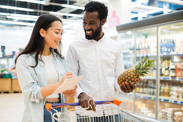 Merci d'acquisto delle coppie multirazziali allegre in supermercato Foto Gratuite