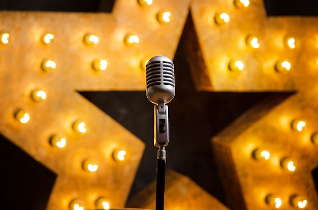 Microfono sul palco del teatro o karaoke, stella luminosa dorata su sfondo Foto Premium