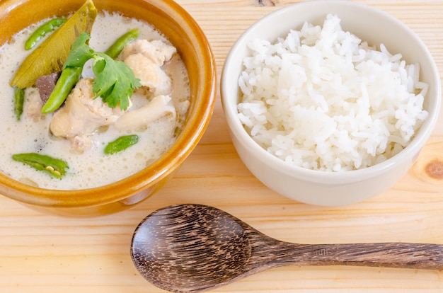 Minestra di pollo tailandese in latte di cocco (tom kha gai) con riso su fondo di legno, alimento tailandese. Foto Premium