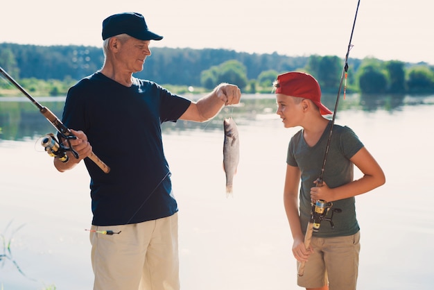 Nonno felice e nipote che pescano sul fiume. Foto Premium