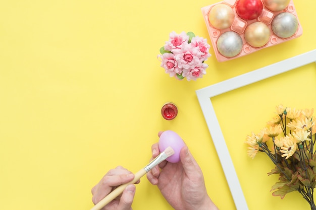 Persona di vista superiore che dipinge l'uovo di pasqua variopinto dipinto in composizione in colori pastello con il pennello Foto Gratuite