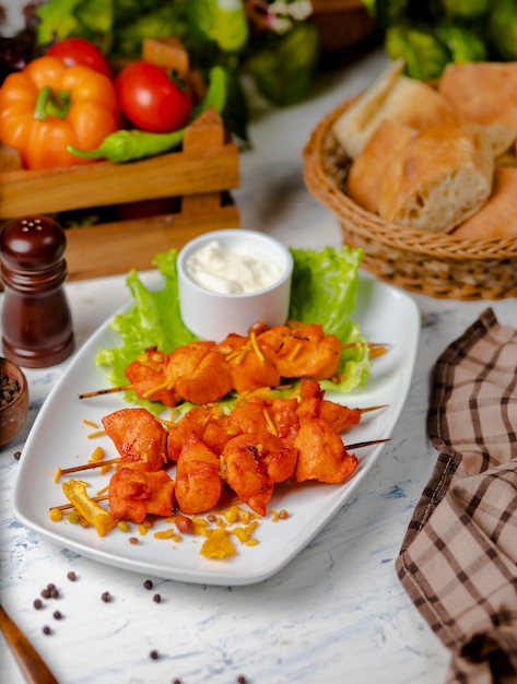 Pezzi di petto di pollo sash kebab, grigliati e serviti con salsa di panna, sumakh e lattuga Foto Gratuite