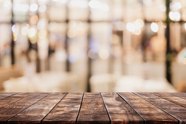 Piano d'appoggio di legno vuoto e caffè vago del bokeh e fondo interno del restaurent con il filtro d'annata Foto Premium