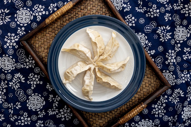 Piatto con dim sum su un supporto di legno su un fondo floreale blu e bianco Foto Gratuite