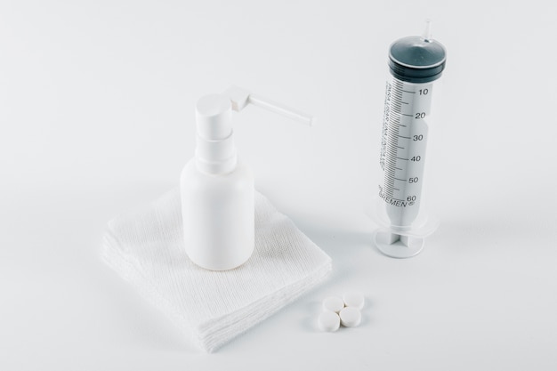 Pillole; spray aerostato bianco su garza medica e siringa vuota per il trattamento su sfondo bianco Foto Gratuite