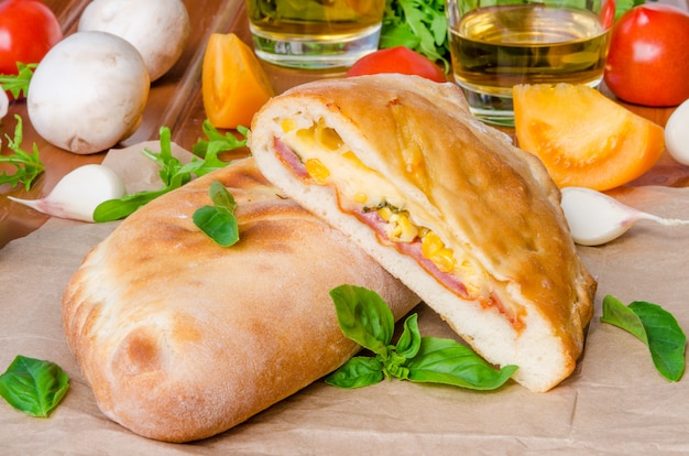 Pizza calzone con salsa di pomodoro, formaggio, erbe, funghi e salsicce. cibo italiano. Foto Premium