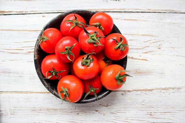 Pomodori rossi organici freschi in banda nera sul tavolo di legno bianco con verde e rosso e peperoncino, peperoni verdi, grani di pepe neri, sale, primi piani, concetto sano Foto Gratuite
