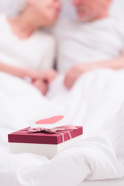 Primo piano del contenitore di regalo con la cartolina d'auguri sulla coperta bianca Foto Gratuite