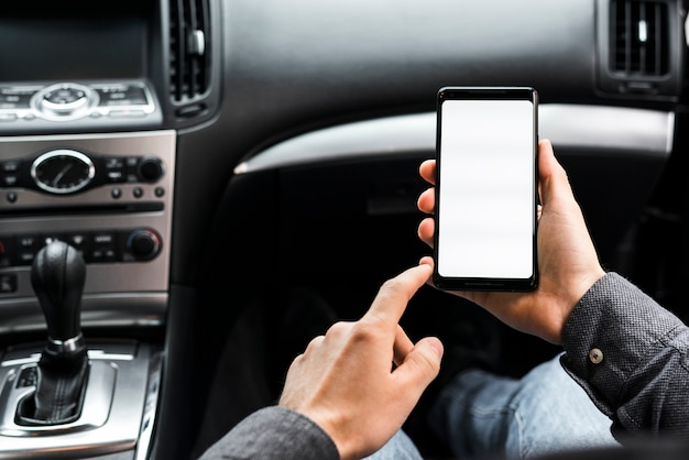 Primo piano della mano utilizzando smartphone con display bianco seduto in macchina Foto Gratuite