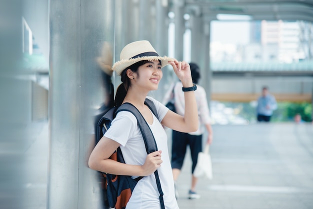 Ragazza asiatica sorridente felice dello studente con lo zaino al fondo della città Foto Gratuite