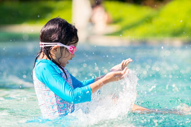 Ragazza del bambino che spruzza sulla piscina con felice. Foto Premium