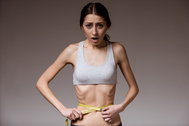 Ragazza magra mostra la sua vita stretta con un metro a nastro in mano Foto Premium
