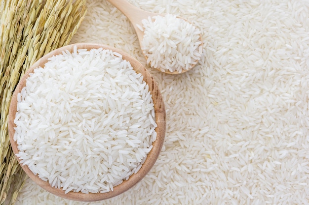 Riso bianco in una ciotola e una borsa, un cucchiaio di legno e una pianta di riso su sfondo bianco di riso Foto Premium