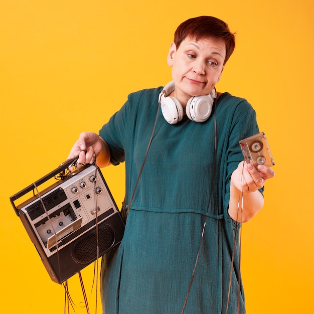 Ritratto del riproduttore di cassette senior della tenuta della donna Foto Gratuite