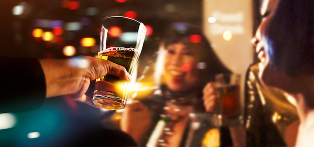 Saluti tintinnio di amici con drink di birra nella notte di festa dopo il lavoro Foto Premium