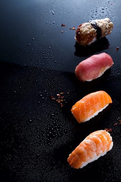 Sashimi, uramaki e nigiri con riso, salmone o tonno, gamberi in nero con gocce d'acqua Foto Premium