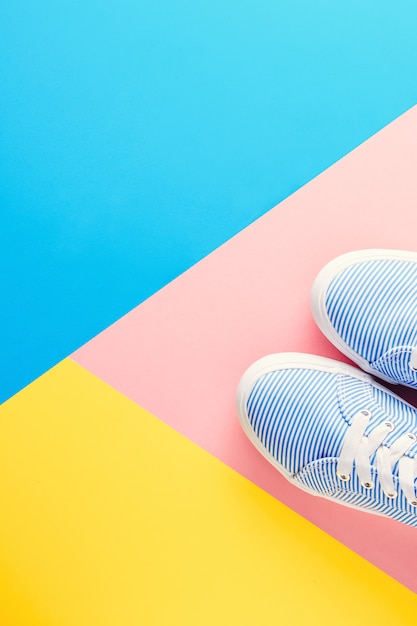 Scarpe da tennis a strisce blu sulla disposizione del pastello di vista superiore del fondo pastello colorata Foto Premium