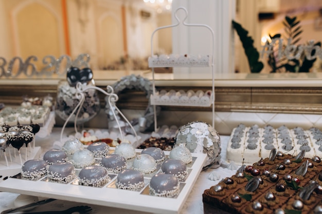 Sweet bar con dessert di mousse grigia, torta al cioccolato e caramelle pop Foto Gratuite