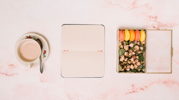 Taccuino con tazza di caffè e scatola con fiori sul tavolo Foto Gratuite