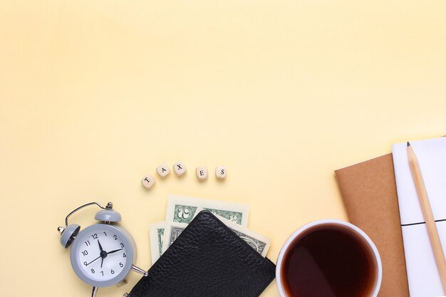 Taccuino con una matita, portafoglio, sveglia, tazza di caffè su uno sfondo beige con le tasse di parola di lettere in legno. Foto Premium