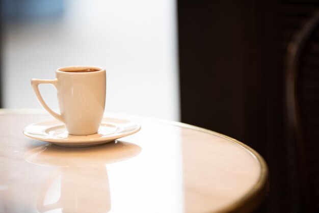 Tazza di caffè bianco su un tavolo di marmo all'interno di un caffè. Foto Premium
