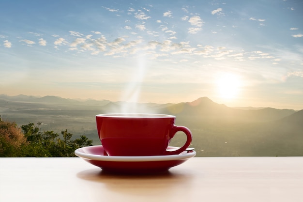 Tazza di caffè rosso con vista montagna sole del mattino Foto Premium