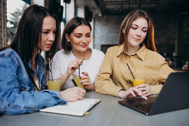 Tre studenti che si preparano per l'esame con il computer portatile in un caffè Foto Gratuite
