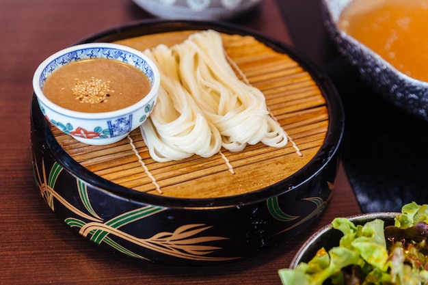 Udon fresco con salsa di sesamo servito in stuoia di bambù con insalata. Foto Premium