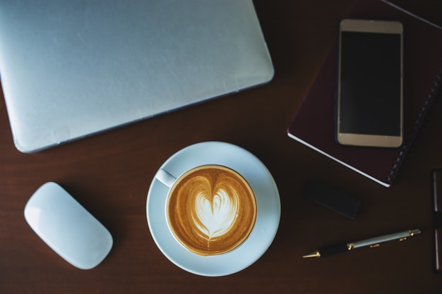 Un caffè latte e un computer portatile sul tavolo. Foto Premium