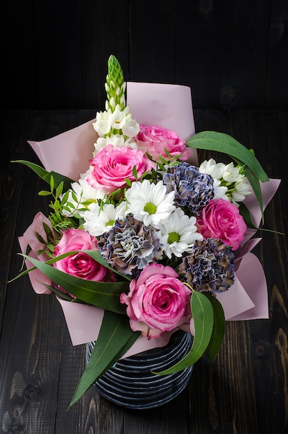 Un Mazzo Di Fiori Su Un Fondo Di Legno Scuro Bouquet Con Rose Foto Premium
