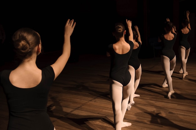 Una danza coreografica di un gruppo di graziose ballerine piuttosto giovani che si esercitano sul palco in una scuola di balletto classico Foto Premium