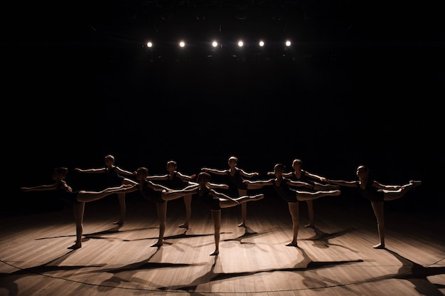 Una danza coreografica di un gruppo di graziose ballerine piuttosto giovani che si esercitano sul palco in una scuola di balletto classico Foto Premium