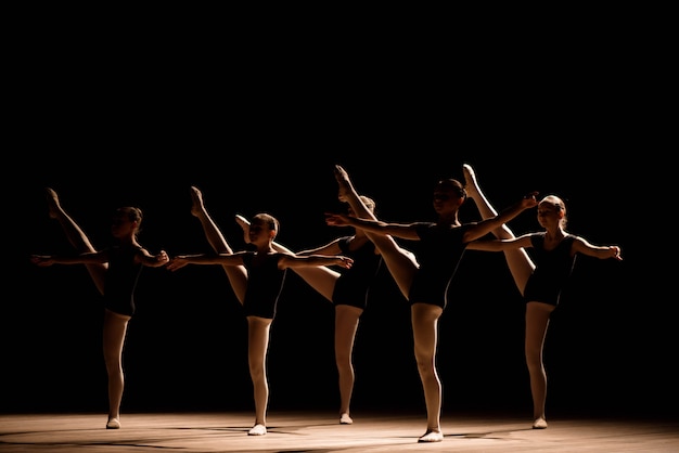 Una danza coreografica di un gruppo di graziose ballerine piuttosto giovani che si esercitano sul palco in una scuola di balletto classico Foto Premium