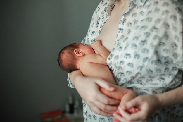 Una giovane madre allatta al seno un bambino. Foto Premium