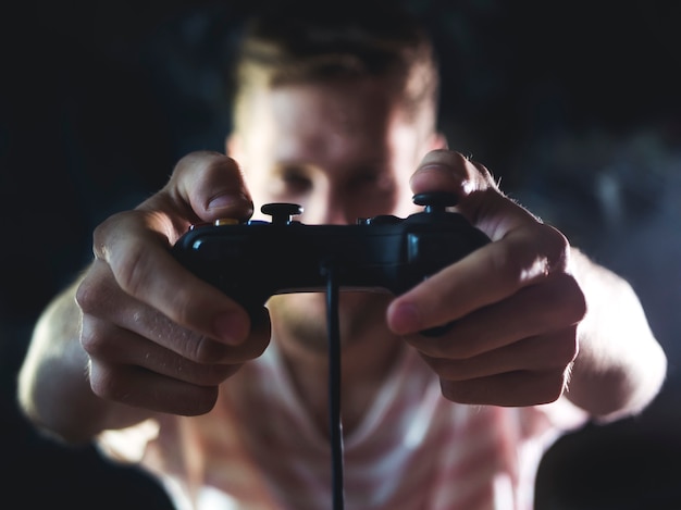 Uomo barbuto con controller per joystick per videogiochi nelle mani davanti al corpo a casa nella notte. Foto Premium