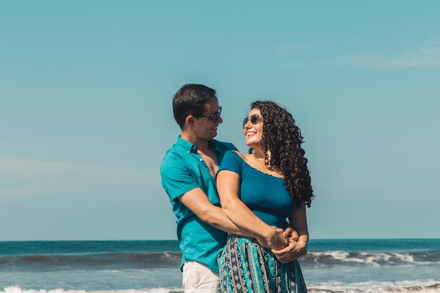 Uomo che abbraccia donna sorridente sulla spiaggia Foto Gratuite