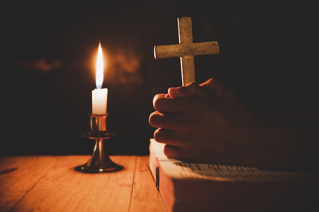 Uomo che prega sulla bibbia nella luce candele messa a fuoco selettiva Foto Gratuite