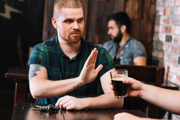 Uomo che rifiuta la bevanda alcolica offerta dal suo amico al bar Foto Gratuite