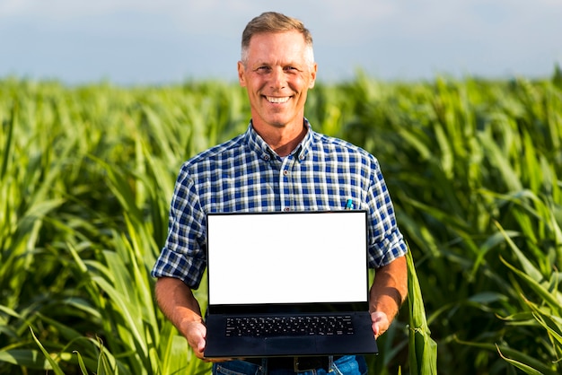 Uomo con un computer portatile in un modello del campo di mais Foto Gratuite