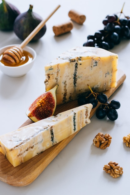 Vecchio formaggio inglese stilton. formaggio blu, fichi e uva su un tagliere di marmo Foto Premium