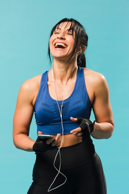 Vista frontale della donna atletica in attrezzatura della palestra che gode della musica Foto Gratuite
