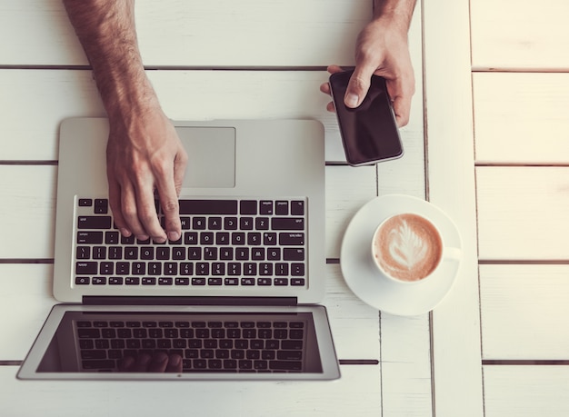 Vista superiore dell'uomo d'affari che per mezzo di un computer portatile e di uno smart phone. Foto Premium