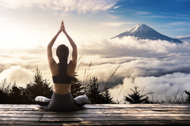 Yoga di pratica della giovane donna nella natura Foto Premium