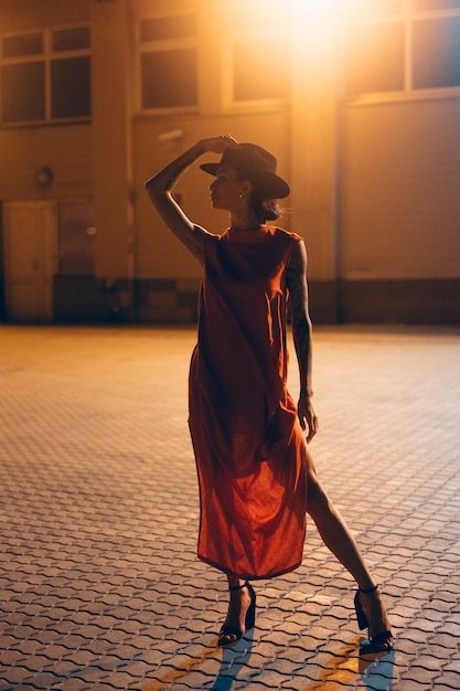 A garota jovem e atraente com um chapéu posa para a câmera à noite Foto gratuita