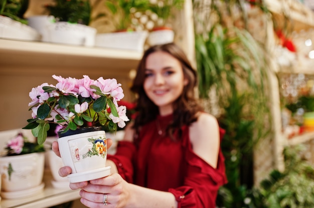 A menina moreno na compra vermelha floresce na loja de flor. Foto Premium