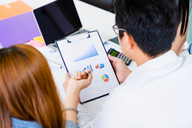 A mulher de negócios nova explica o detalhe do plano de marketing na folha de dados para team com o portátil na tabela. Foto Premium